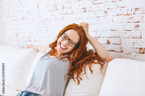 junge glückliche freudige lachende frau mit roten haaren auf der couch portrait