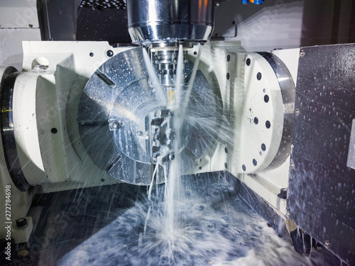 5-axis cnc milling machine at work with coolant under pressure and motion blur of streams.. photo