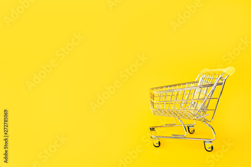 Toy cart for products on a yellow background. Place for text. View from above. The concept of shopping and consumption