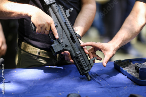 Фотография .Details with the hands of a man holding an automatic rifle.