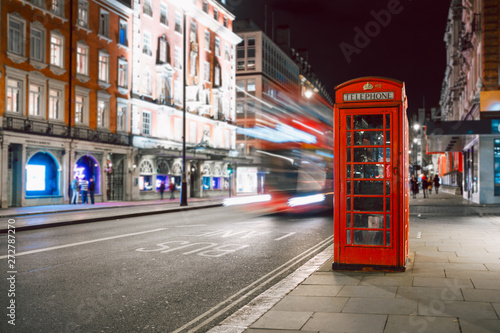 Light trails of a double decker bus next to the iconic telephone booth in London