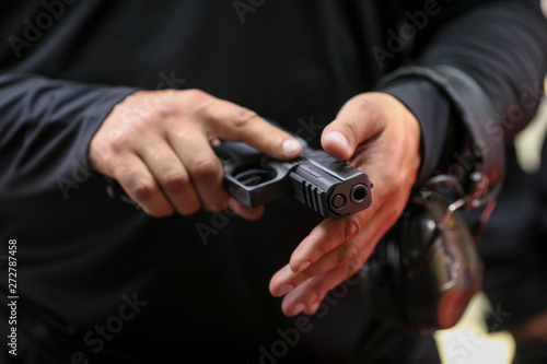 Details with the hands of a man handling a 9mm handgun