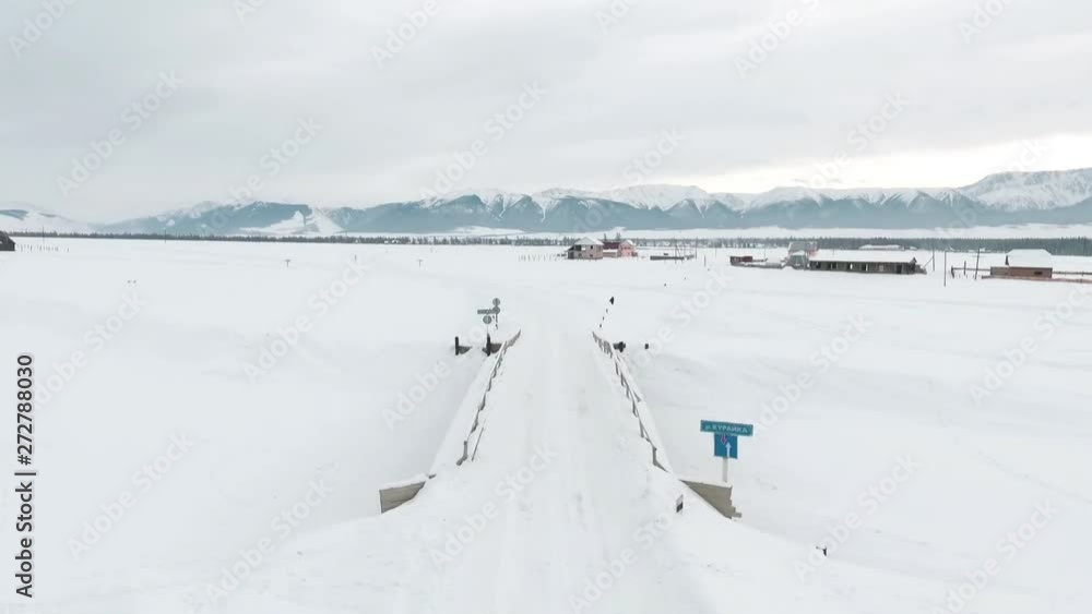 Aerial view. Flying over the snow-covered Altai village. Winter. Siberia. Altai.