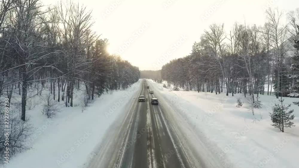 Aerial View. Flying over the mountain road on which the cars go. Winter. Winter road. Cars go on a snow-covered road. Aerial View. Flying over the mountain road on which the cars go. Winter. Winter road. Cars go on a snow-covered road.