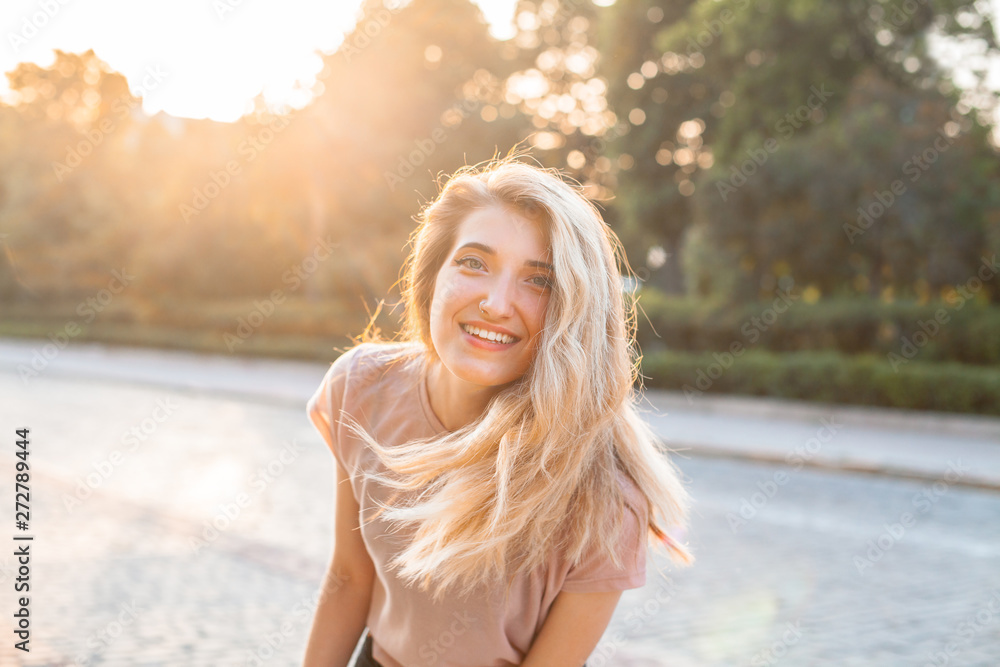 Cheerful young woman walking in the city under sunset light