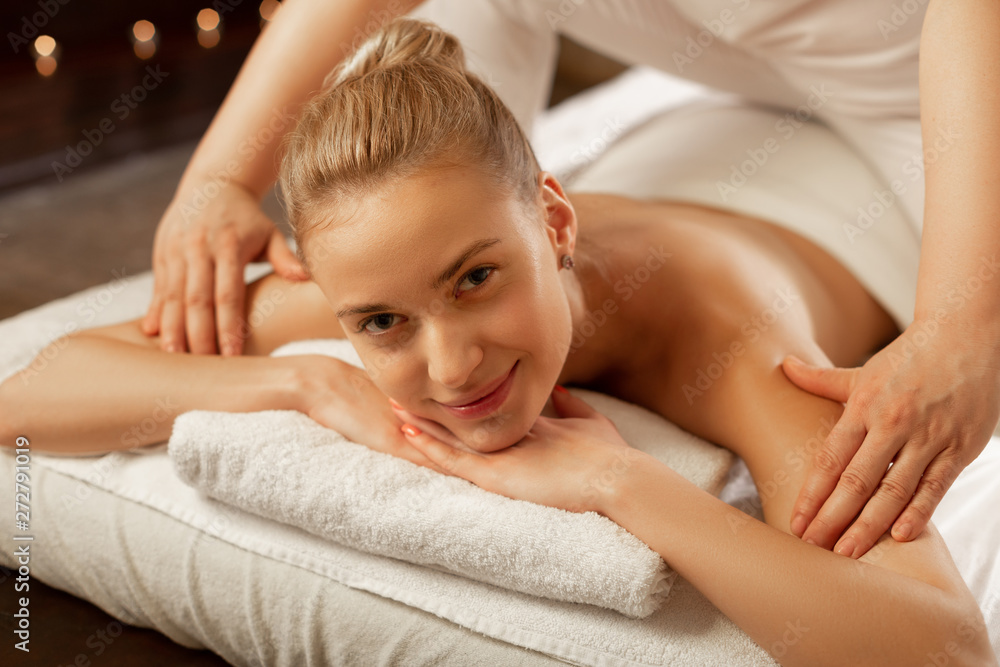 Smiling good-looking naked girl lying on white towels while massage master Smiling good-looking naked girl lying on white towels while massage master