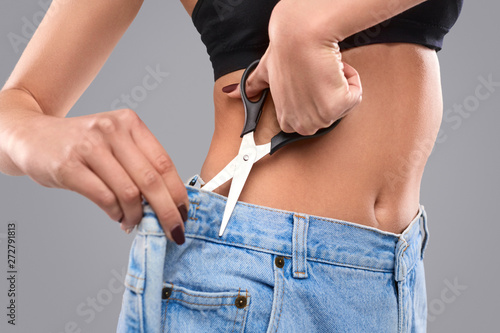 Crop woman cutting excess jeans