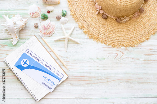 Vacation travel equipment Straw hat and marine objects, shells, starfish, passport on light wooden floor. Platform with copy space. Summer vacation concept.