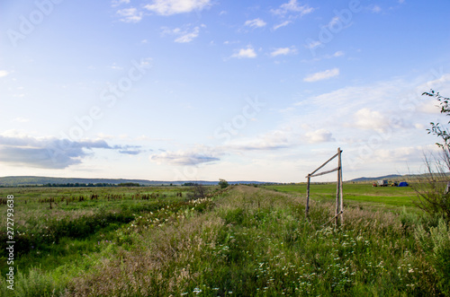 Cloudy blue sky on the horizon of Russian fields and mountains. Summer forest on a sunny day.