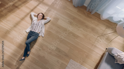 Obraz na płótnie Young Woman is Lying on a Wooden Flooring in an Apartment