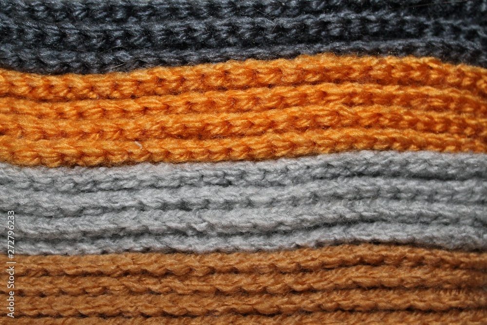 A pile of bright orange, gray and brown knitted elements. Warm and soft wallpaper, pattern, background A pile of bright orange, gray and brown knitted elements. Warm and soft wallpaper, pattern, background
