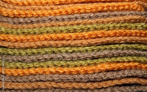 A pile of bright orange, green and brown knitted elements. Warm and soft wallpaper, pattern, background © lipchania
