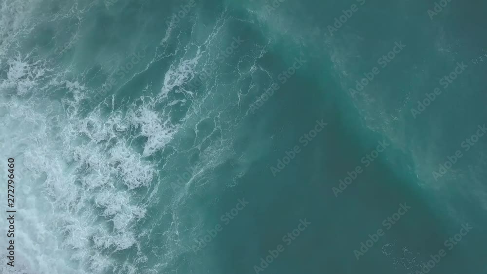 Aerial top view turquoise sea waves break on empty sand beach. Clean sea waves from bird's eye view, ocean waves reaching shore and splashing from above Aerial top view turquoise sea waves break on empty sand beach. Clean sea waves from bird's eye view, ocean waves reaching shore and splashing from above