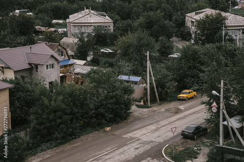 Zhiguli yellow car parked on the road, modern Russia summer day, brick and wooden buildings of the inhabitants of Upper Pyshma | UPPER PYSHMA, RUSSIA - 15.08.2018. photo