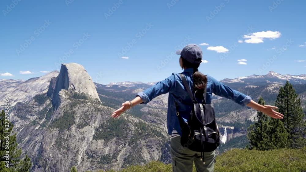 back view of young happy asian female hiker reaching goal at mountain top. Standing against beautiful landscape with blue sky in half dome trail enjoy view in yosemite national park summer trip. back view of young happy asian female hiker reaching goal at mountain top. Standing against beautiful landscape with blue sky in half dome trail enjoy view in yosemite national park summer trip.