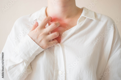 Young woman scratching the itch on her chest and neck w/ redness rash. Cause of itchy skin include dermatitis, food/drugs allergies, dry skin or insect bites. Health care concept. Close up.