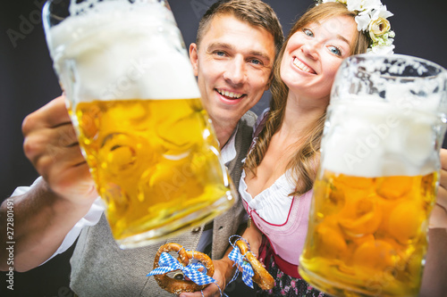  Mann und Frau stoßen mit Maß bier an und lachen auf dem Oktoberfest 