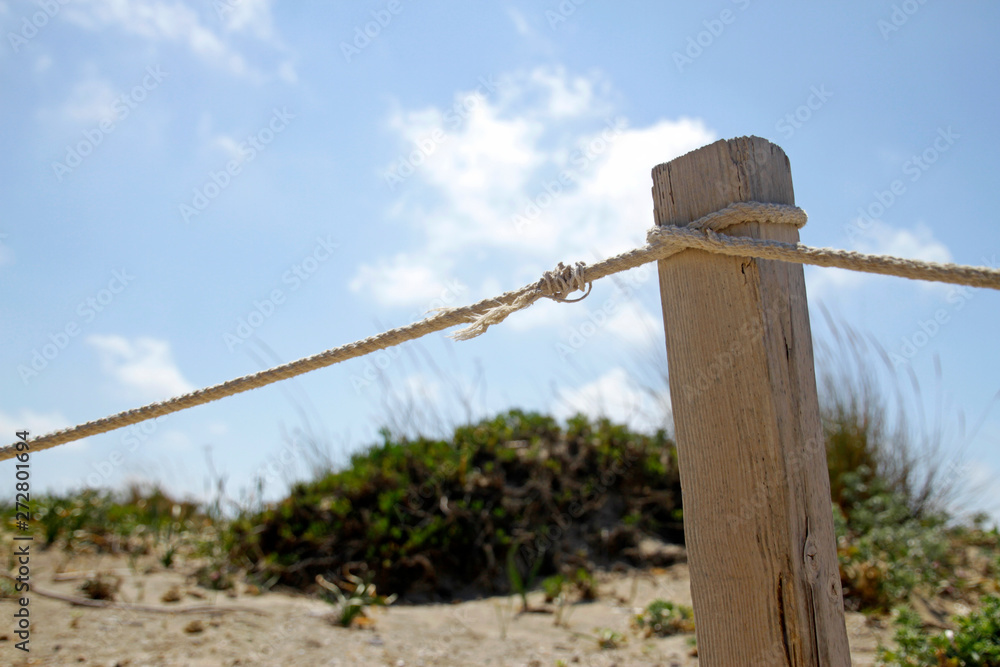 Wooden post with rope at the beach on a sunny day Wooden post with rope at the beach on a sunny day