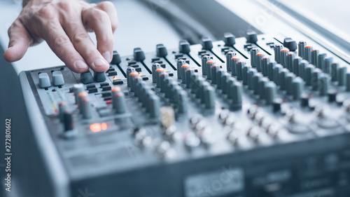 Professional sound console. Closeup of man hand mixing tracks, adjusting tune effects.