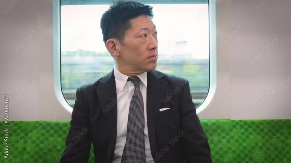 Japanese businessman riding in a train. Tokyo passing by in the window. Japanese businessman riding in a train. Tokyo passing by in the window.