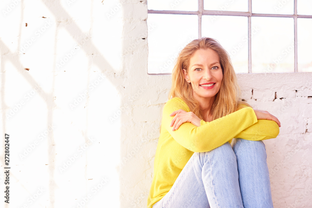 Fototapeta premium Happy middle aged woman sitting on the floor and relaxing