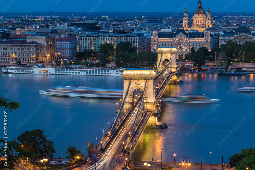 Budapest urban scape with the Basilica, Devil's Wheel and the illuminated Chain Bridge across the Danube River by night.