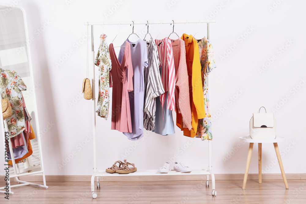 Women's hip clothing store interior concept. Row of different colorful female clothes hanging on rack in hipster fashion show room in shopping mall. White wall background. Copy space.
