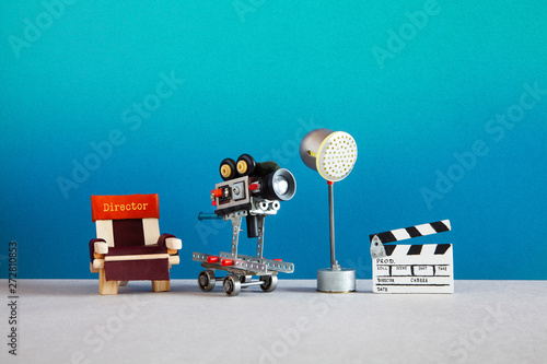 Motion picture backstage area with director's chair, camera or camcorder on wheels, the lighting projector spotlight and clapperboard. Filmmaking behind the scenes