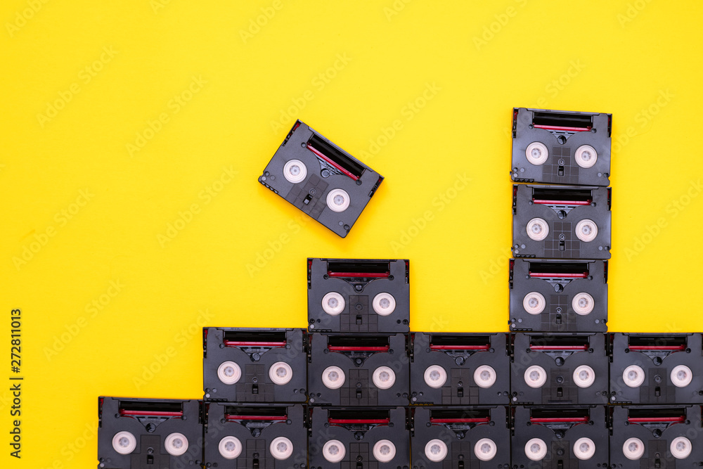 Obraz premium Vintage mini DV cassette tapes used for filming back in a day. Pattern made of plastic video tapes on yellow background