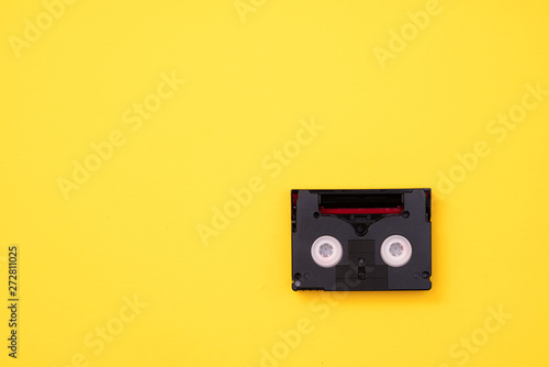 Vintage mini DV cassette tape used for recording video back in a day. Plastic, magnetic, analog film tape on yellow background photo
