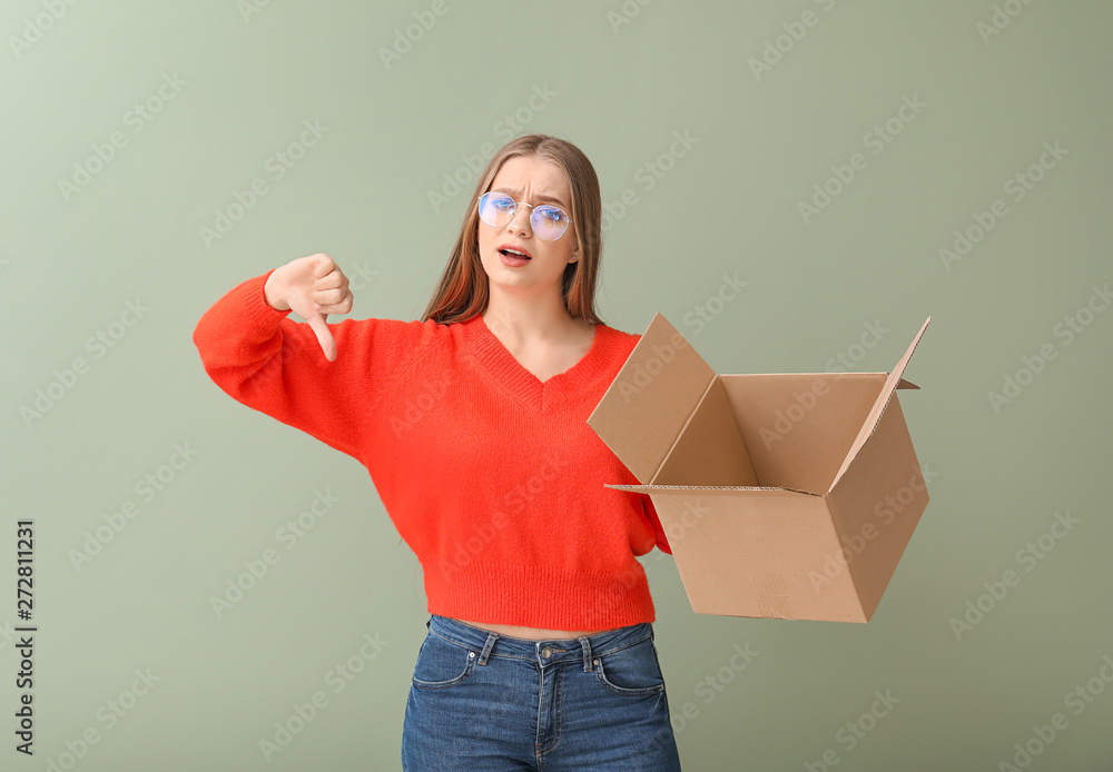 Young woman with cardboard box showing thumb-down on color background Young woman with cardboard box showing thumb-down on color background