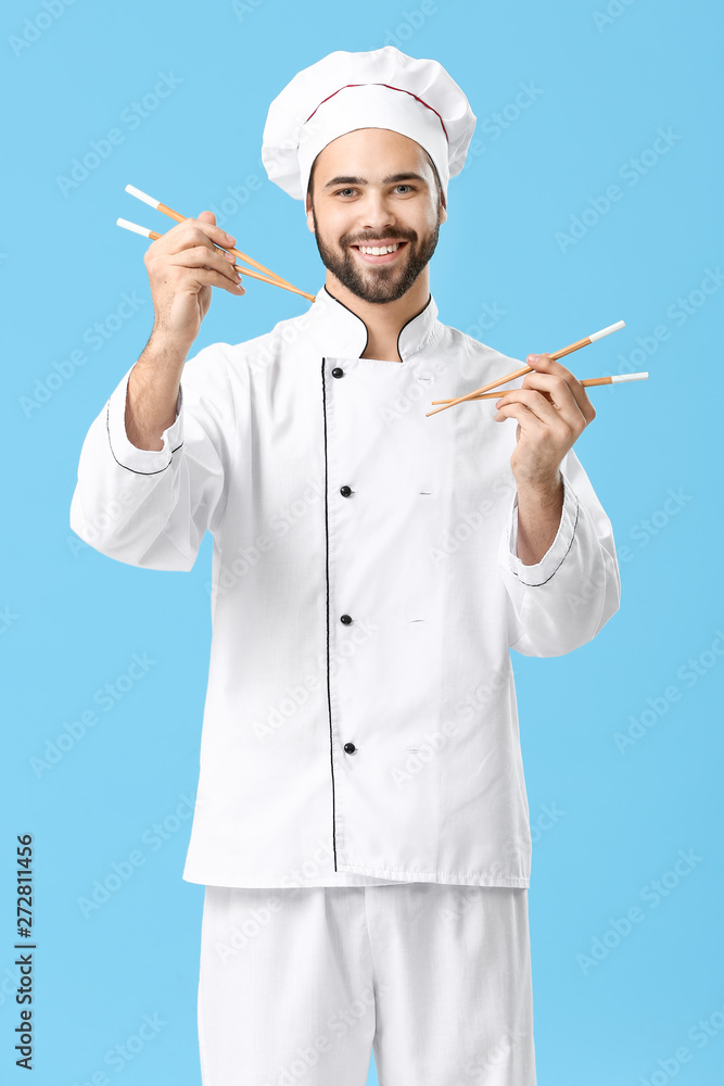 Handsome male chef with chopsticks on color background Handsome male chef with chopsticks on color background