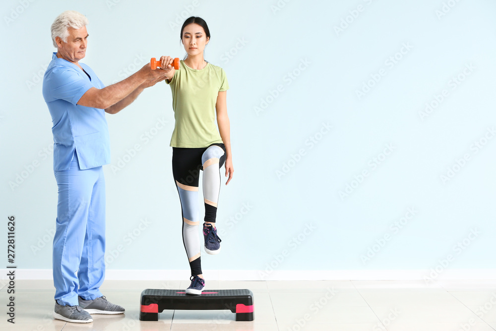 Mature physiotherapist working with young Asian woman in clinic Mature physiotherapist working with young Asian woman in clinic