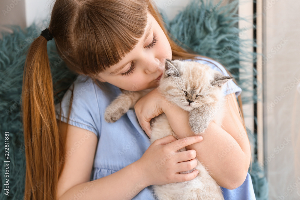 Girl with cute fluffy kitten near window