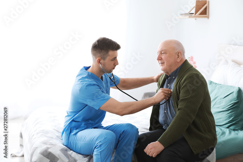 Medical worker examining senior man in nursing home