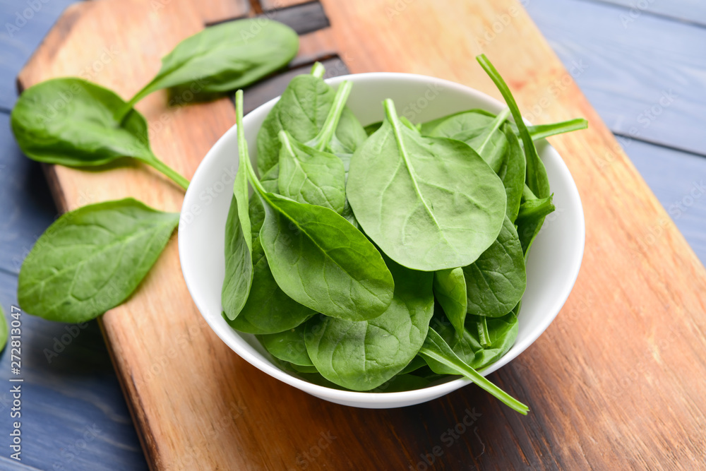 Bowl with fresh spinach on wooden board Bowl with fresh spinach on wooden board