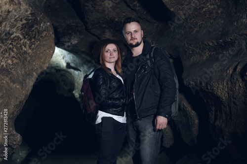 Young couple exploring huge cave. Adventure travellers dressed cowboy hat and backpack, leather jacket. extreme vacation, tourist route. ancient crystal formations, geology, village Kryvche. Ukraine