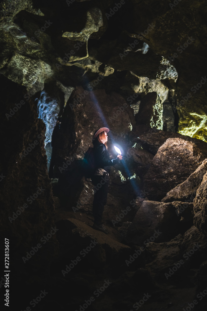 Obraz premium Girl exploring huge cave. Adventure traveller dressed cowboy hat and backpack, leather jacket. extreme vacation, tourist route. ancient crystal formations, vertical photo, village Kryvche. Ukraine