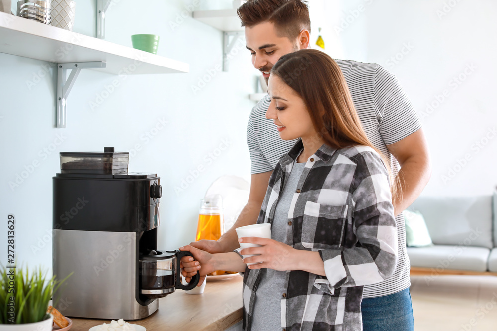 Young couple using coffee machine in kitchen Young couple using coffee machine in kitchen