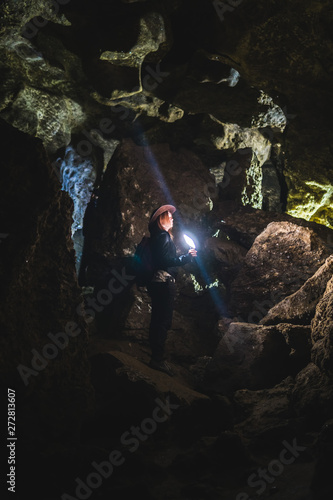 Girl exploring huge cave. Adventure traveller dressed cowboy hat and backpack, leather jacket. extreme vacation, tourist route. ancient crystal formations, vertical photo, village Kryvche. Ukraine