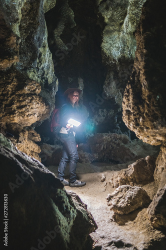 Girl exploring huge cave. Adventure traveller dressed cowboy hat and backpack, leather jacket. extreme vacation, tourist route. ancient crystal formations, vertical photo, village Kryvche. Ukraine