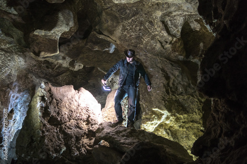 Man exploring huge cave. Adventure travellers dressed cowboy hat and leather jacket. extreme vacation  tourist route. ancient crystal formations  danger geology  village Kryvche. Ukraine