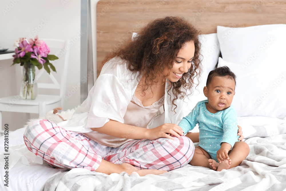 Happy African-American mother with cute little baby in bedroom Happy African-American mother with cute little baby in bedroom