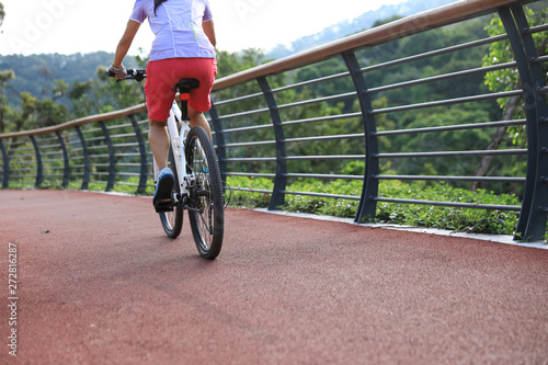 Fototapeta Naklejka Na Ścianę i Meble -  Woman cyclist riding mountain bike on forest trail