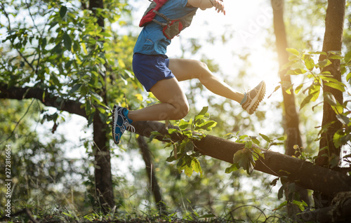 Sportswoman ultramarathon cross country trail running in tropical autumn forest