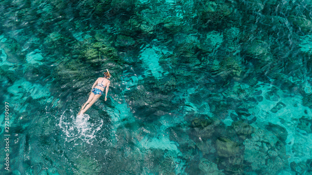 Woman swimming in blue sea. Snorkeling girl in full-face snorkeling mask. Coral reef in shallow sea. Snorkel undersea. Seashore underwater photo. Active seaside vacation. Water sport in tropical sea.