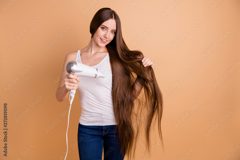 Close up photo beautiful amazing her she lady arms hands hold very long hair curl drying equipment enjoy easy simple process wear casual white tank-top jeans denim isolated pastel beige background Close up photo beautiful amazing her she lady arms hands hold very long hair curl drying equipment enjoy easy simple process wear casual white tank-top jeans denim isolated pastel beige background
