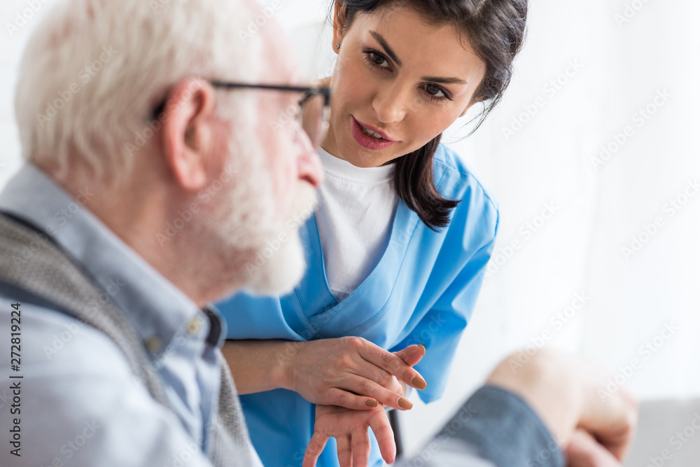Selective focus of calm nurse talking to elderly patient Selective focus of calm nurse talking to elderly patient