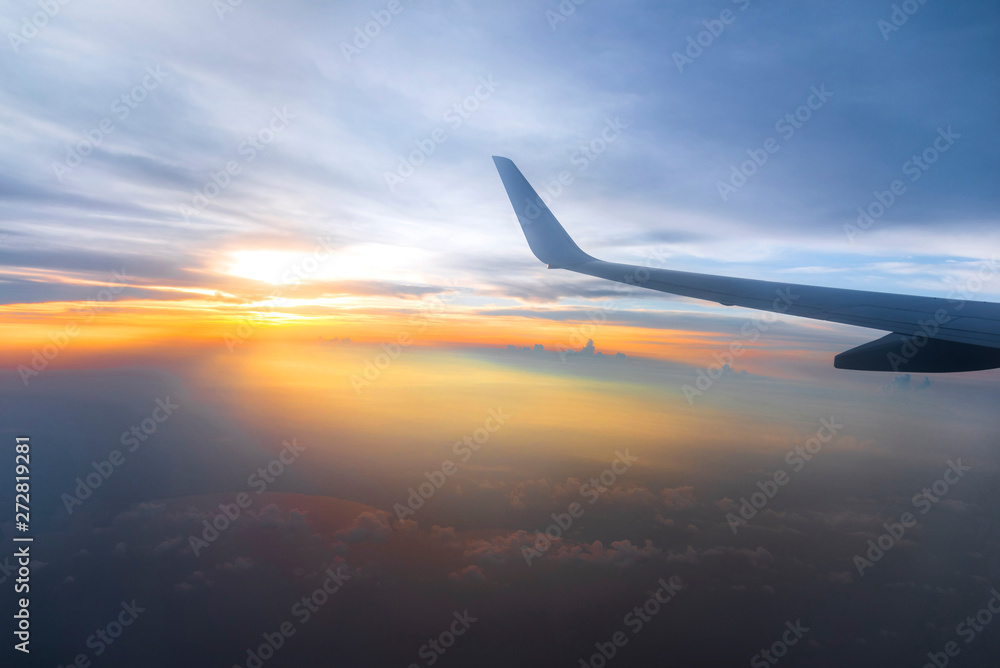 Wing of the air plane on the sea of cloud sunset sky background from window airplane