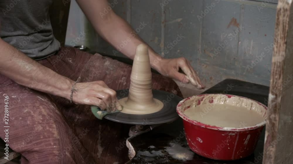 The potter makes a jug of clay. Ceramist. A man makes a vase on a potter's wheel. Hands of the master turn a piece of clay into a jug. Handwork. Pottery. Sculptor's wet hands close up. Clay dishes The potter makes a jug of clay. Ceramist. A man makes a vase on a potter's wheel. Hands of the master turn a piece of clay into a jug. Handwork. Pottery. Sculptor's wet hands close up. Clay dishes